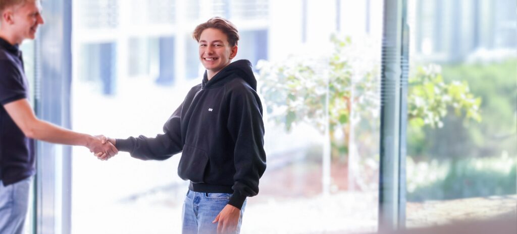 Ein junger Mann in einem schwarzen Hoodie, der in einem modernen BĂĽro ist.